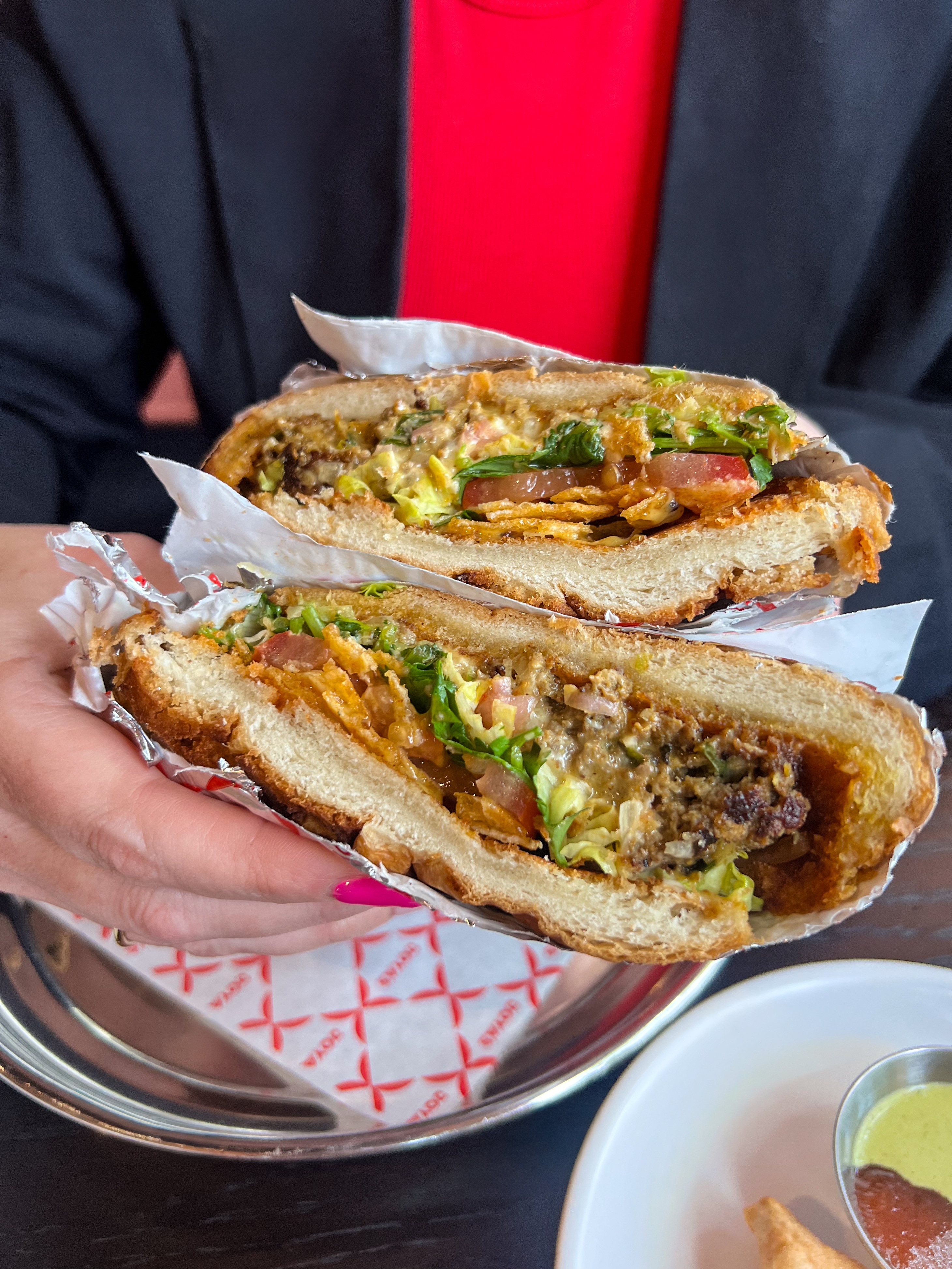 Hearty open-faced sandwich or torta filled with seasoned meat, fresh vegetables, and vibrant green sauce