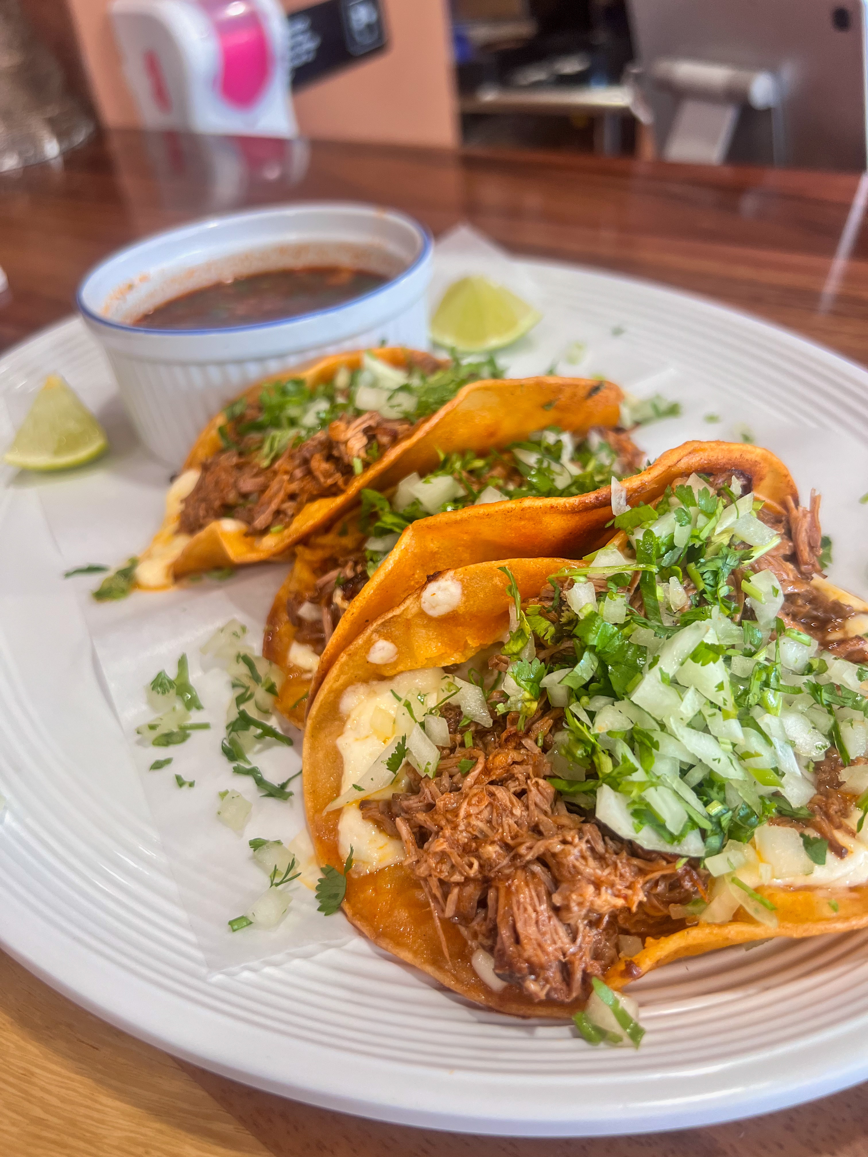 Trio of street-style tacos filled with tender shredded meat, topped with fresh cilantro and diced white onions