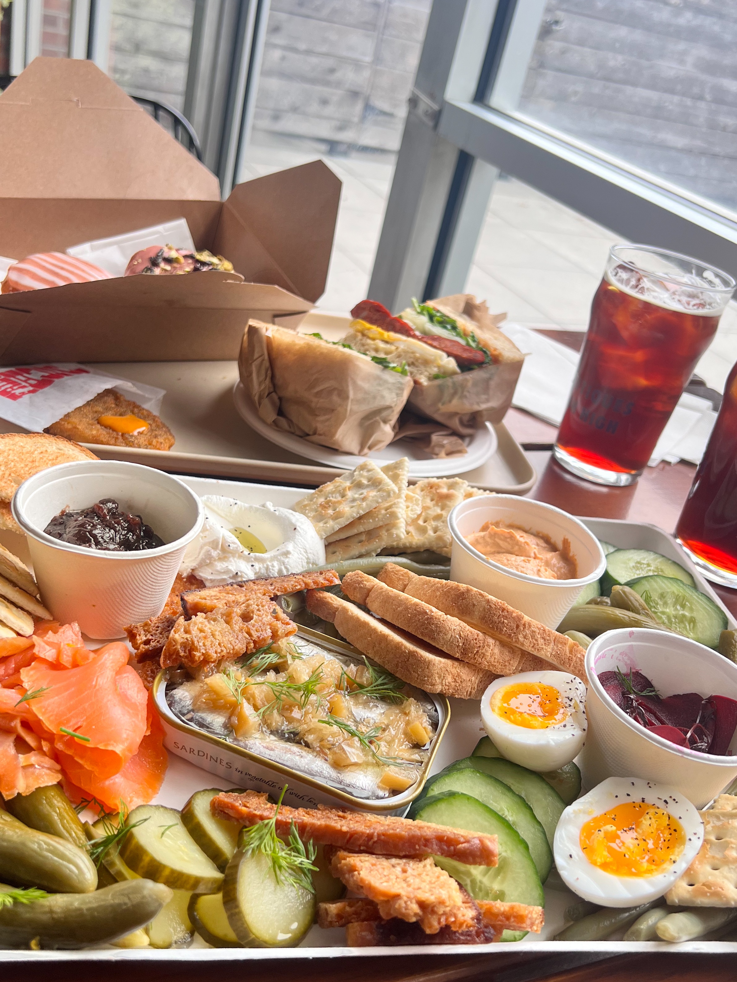 Lavish charcuterie board or appetizer tray with small sandwiches, deviled eggs, pickled vegetables, dips, and smoked salmon